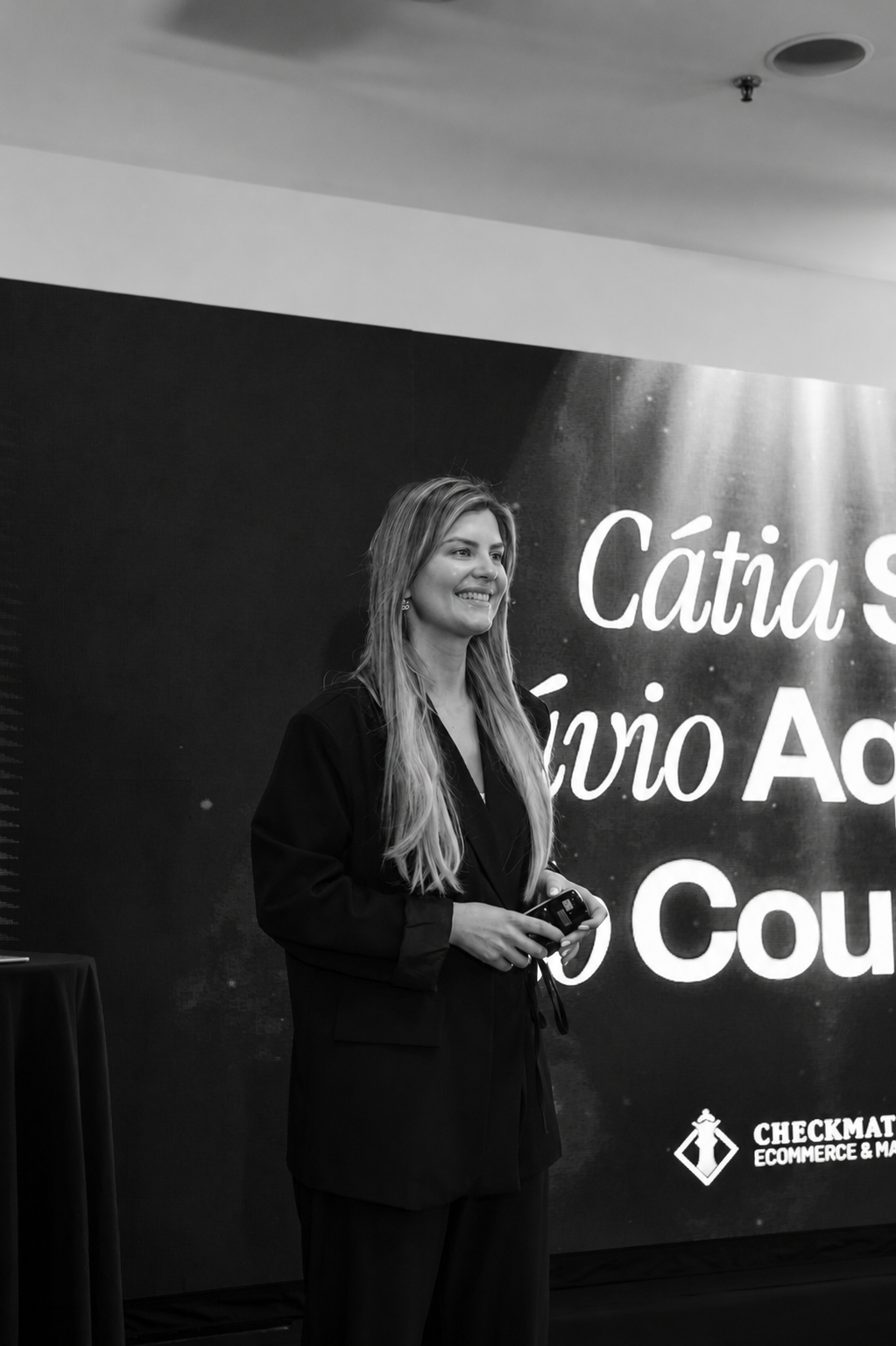 Cátia before a live presentation with the event screen behind her.